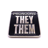 Picture shows frontside of pronouns badge - "PRONOUNS /  THEY/ THEM" silver metal and black enamel