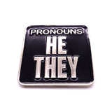 Picture shows frontside of pronouns badge - "PRONOUNS / HE/ THEY" silver metal and black enamel