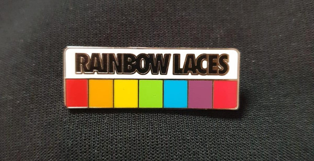 A pin badge with the colours of the rainbow and the words "Rainbow Laces" in bold.